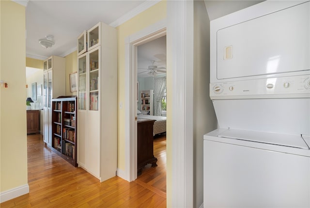 laundry room with ceiling fan, ornamental molding, stacked washer and dryer, and light hardwood / wood-style flooring