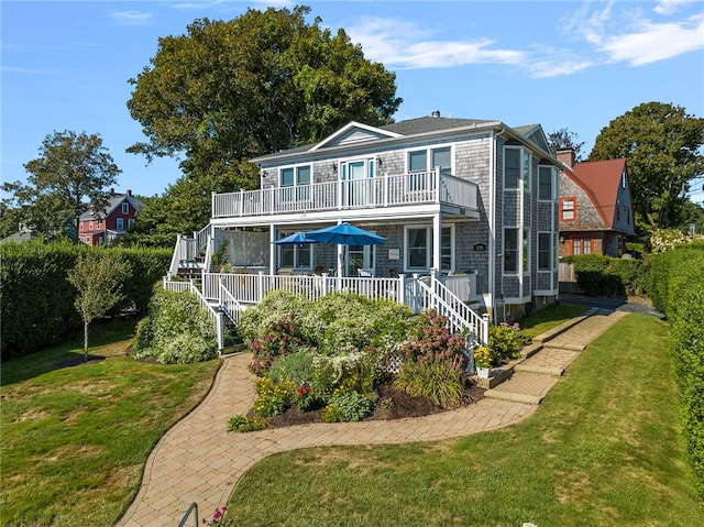 back of house featuring a lawn and a balcony