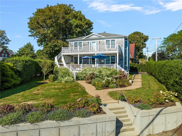 view of front of property featuring a porch, a balcony, and a front lawn