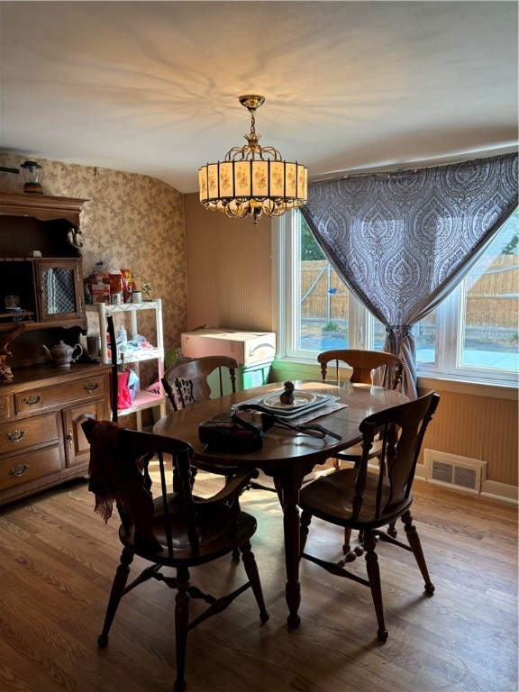 dining room with light wood-type flooring, plenty of natural light, vaulted ceiling, and a chandelier