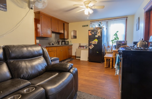 living room with ceiling fan, light wood-type flooring, and sink