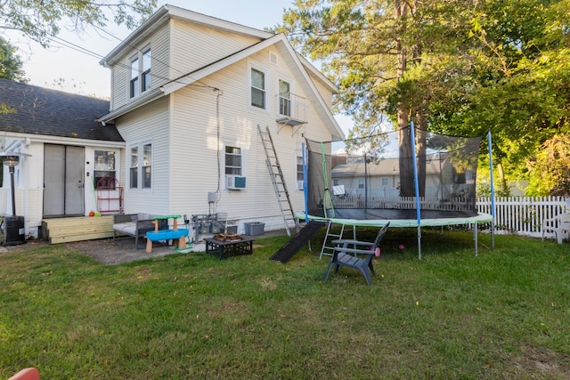 rear view of house with cooling unit, a trampoline, a yard, and a patio area