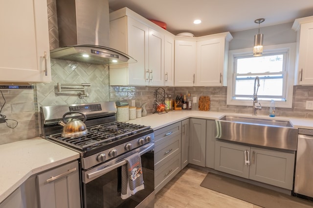 kitchen with stainless steel appliances, wall chimney range hood, white cabinets, and gray cabinets