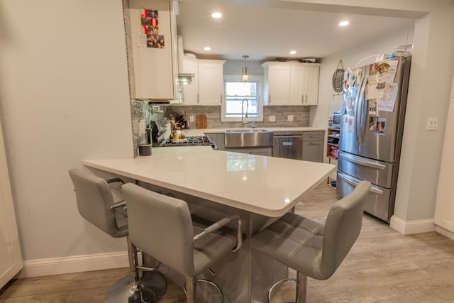 kitchen with pendant lighting, kitchen peninsula, appliances with stainless steel finishes, and sink