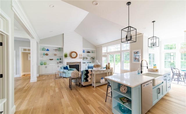 kitchen featuring light hardwood / wood-style floors, a center island with sink, sink, hanging light fixtures, and stainless steel dishwasher