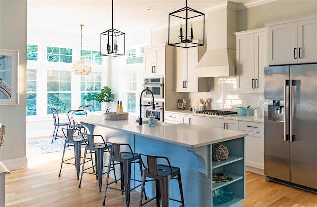 kitchen featuring pendant lighting, a center island with sink, stainless steel appliances, and white cabinets