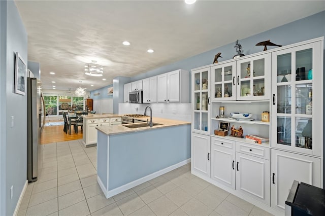 kitchen featuring tasteful backsplash, sink, stainless steel appliances, kitchen peninsula, and white cabinets