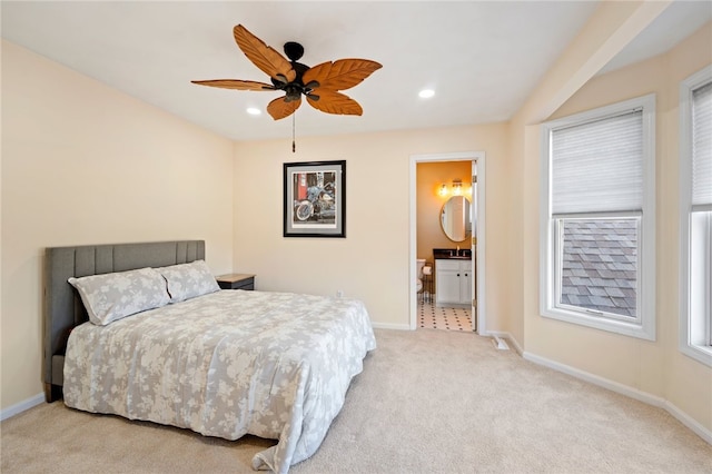 bedroom with ceiling fan, connected bathroom, and light carpet