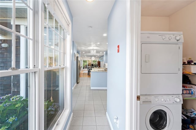 clothes washing area with stacked washer and clothes dryer and light tile patterned floors