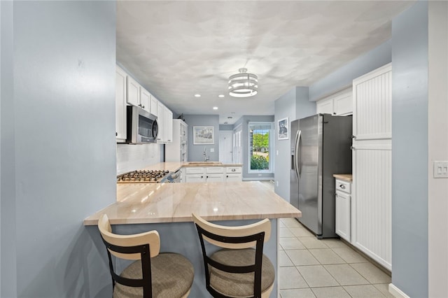 kitchen featuring stainless steel appliances, white cabinets, sink, kitchen peninsula, and a kitchen breakfast bar