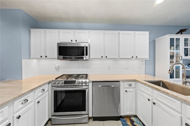 kitchen featuring tasteful backsplash, white cabinets, appliances with stainless steel finishes, and sink