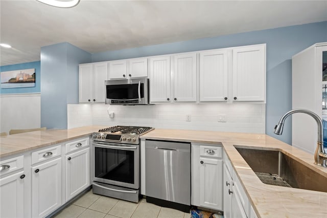 kitchen featuring stainless steel appliances, light tile patterned flooring, white cabinets, and sink