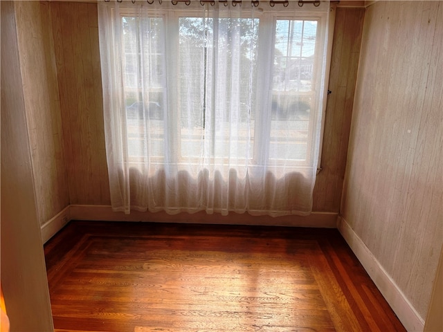 unfurnished room with hardwood / wood-style flooring and wooden walls