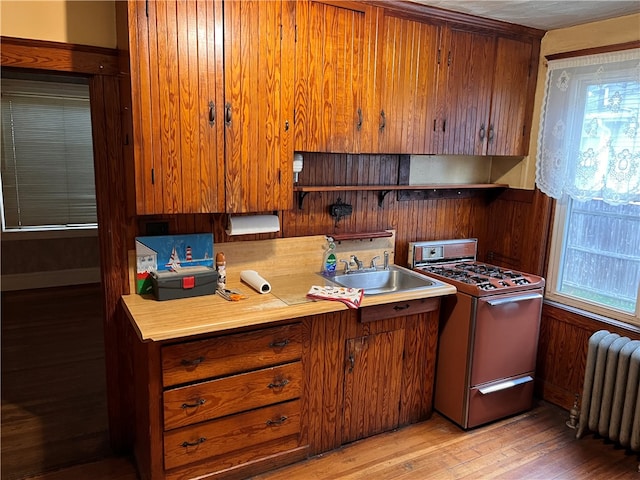 kitchen featuring radiator, sink, white range, and light hardwood / wood-style floors