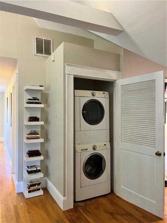 clothes washing area featuring stacked washer / drying machine and hardwood / wood-style flooring