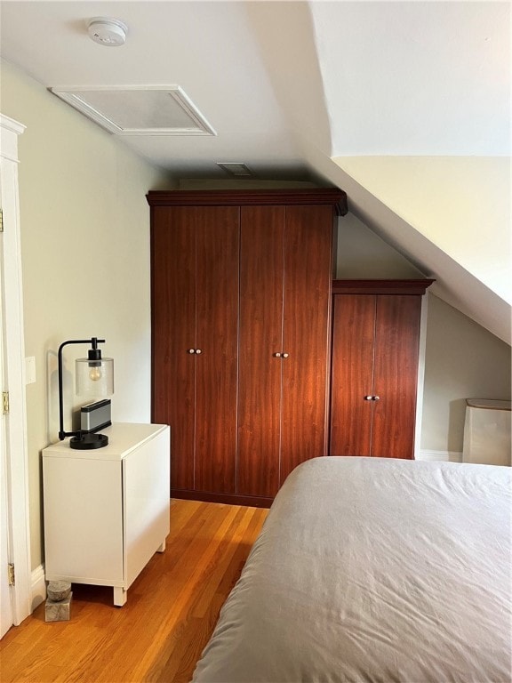 bedroom with a closet, lofted ceiling, and light hardwood / wood-style flooring