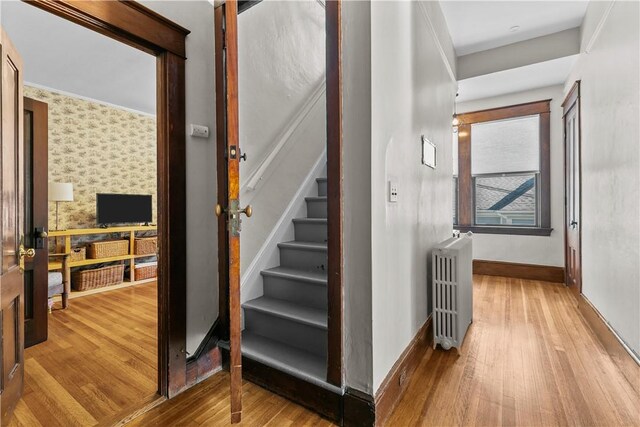68 Kay St, Newport, RI 02840 - staircase with radiator heating unit, baseboards, wallpapered walls, and hardwood / wood-style flooring