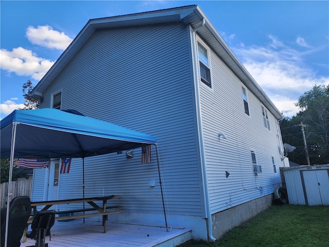 rear view of property featuring a gazebo, a wooden deck, and a storage unit