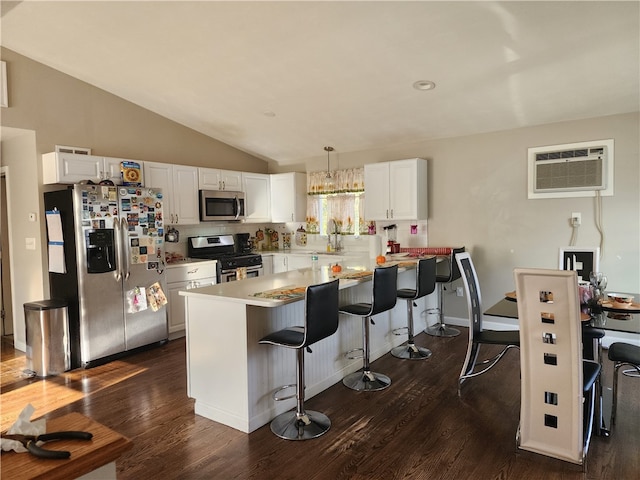 kitchen featuring white cabinets, stainless steel appliances, hanging light fixtures, and dark wood-type flooring