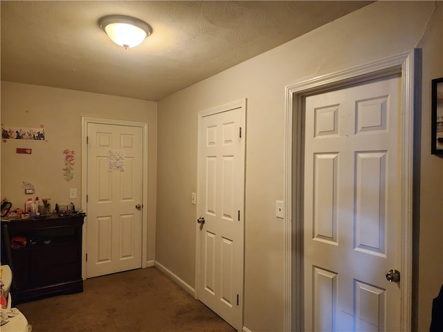 hallway featuring dark carpet and a textured ceiling