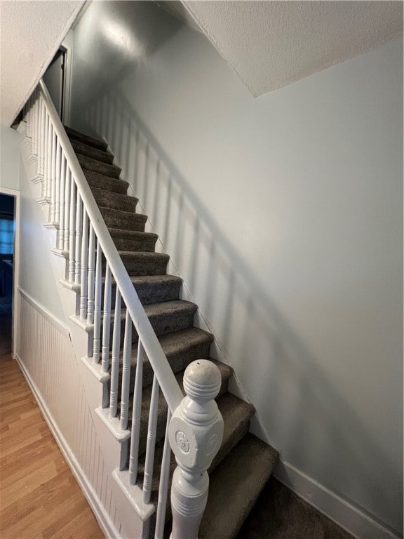 stairway featuring a textured ceiling and wood-type flooring