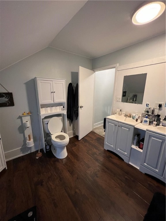 bathroom with vanity, toilet, hardwood / wood-style flooring, and vaulted ceiling