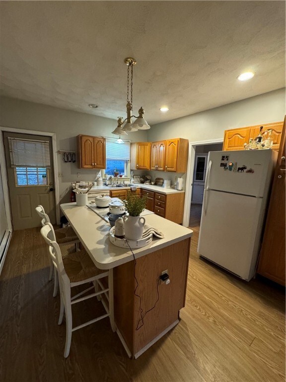 kitchen with light hardwood / wood-style flooring, pendant lighting, a notable chandelier, a center island, and white refrigerator