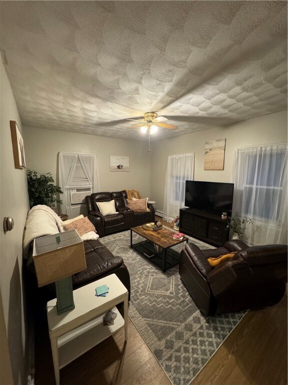 living room featuring ceiling fan, wood-type flooring, and a textured ceiling