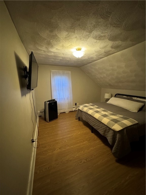 bedroom with lofted ceiling, a textured ceiling, and hardwood / wood-style flooring