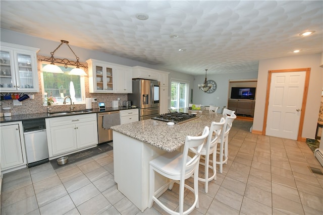 kitchen featuring stainless steel appliances, decorative backsplash, decorative light fixtures, and white cabinets