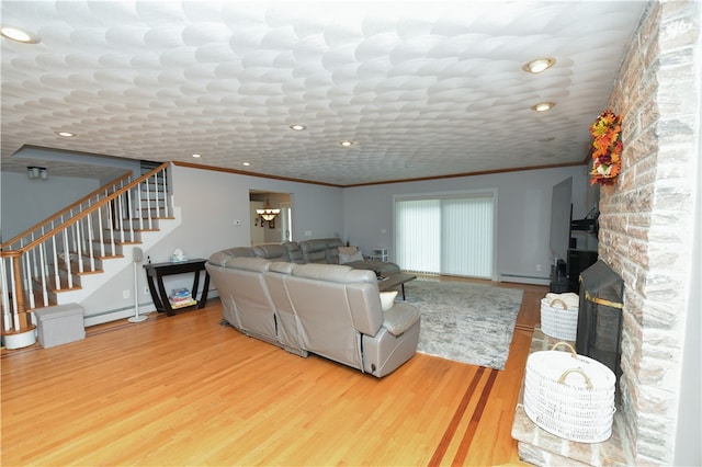 living room featuring crown molding, hardwood / wood-style flooring, baseboard heating, and a fireplace