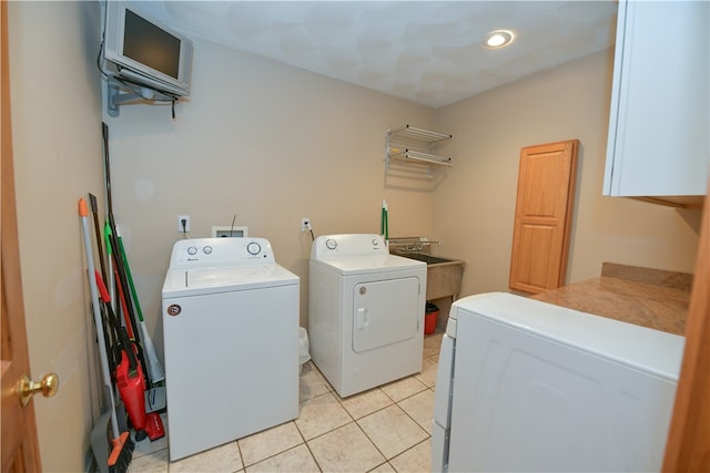 laundry room with sink, light tile patterned floors, cabinets, and separate washer and dryer