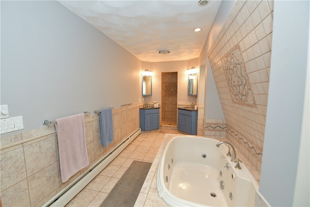 bathroom featuring tile walls, a relaxing tiled tub, vanity, baseboard heating, and tile patterned flooring