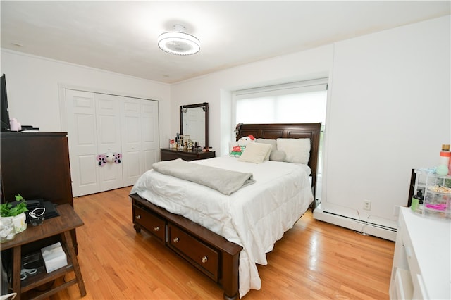 bedroom with a closet, a baseboard heating unit, and light wood-type flooring