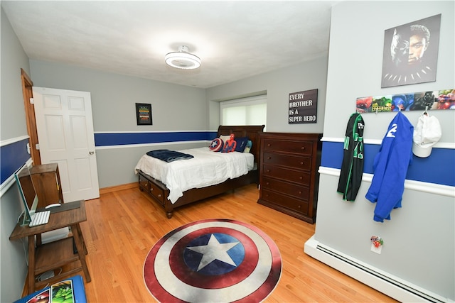 bedroom with a baseboard heating unit and light wood-type flooring