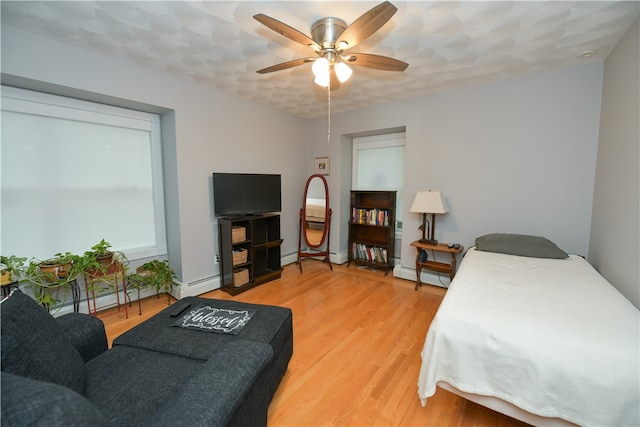 bedroom featuring ceiling fan, wood-type flooring, and a baseboard radiator