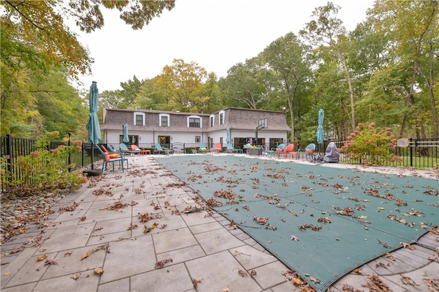 rear view of house featuring a patio and a covered pool