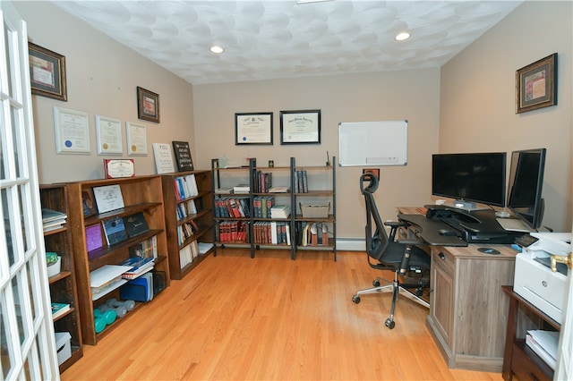 office space with baseboard heating, a textured ceiling, and light wood-type flooring