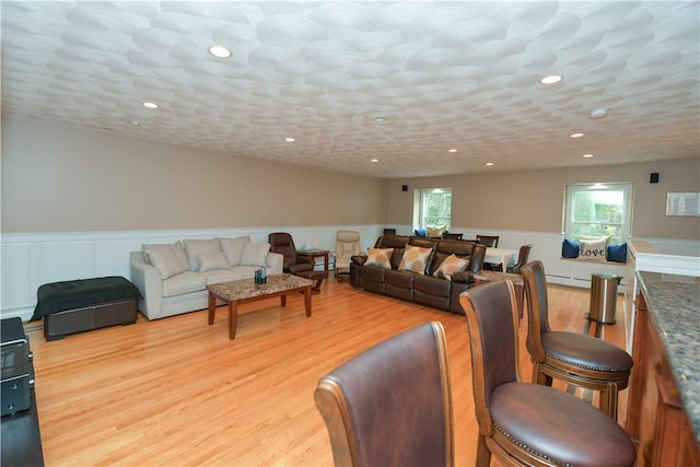 living room with a baseboard heating unit, a textured ceiling, and light wood-type flooring