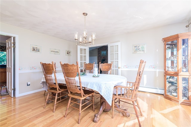 dining area with light wood-type flooring, a notable chandelier, french doors, and a baseboard heating unit