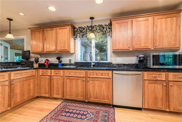 kitchen with light wood-type flooring, appliances with stainless steel finishes, sink, and decorative light fixtures