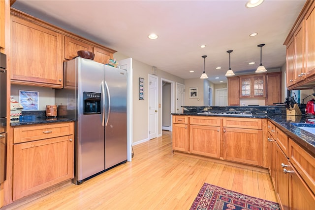 kitchen featuring a baseboard heating unit, light hardwood / wood-style floors, hanging light fixtures, appliances with stainless steel finishes, and dark stone counters