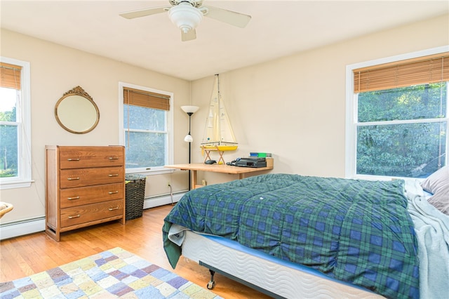 bedroom featuring ceiling fan, a baseboard radiator, and light wood-type flooring