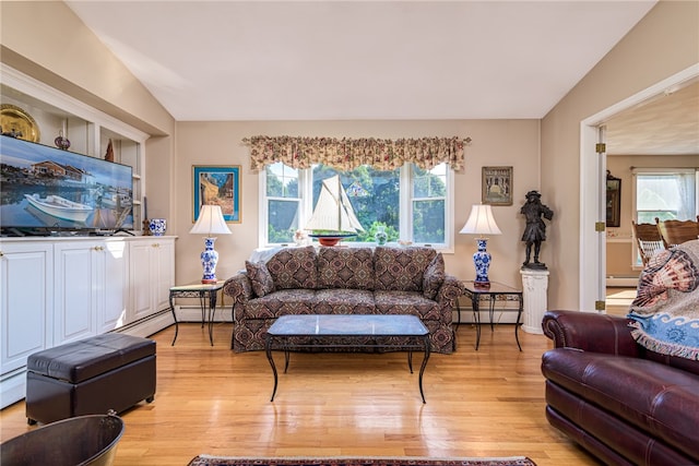 living room featuring lofted ceiling, baseboard heating, and light hardwood / wood-style floors