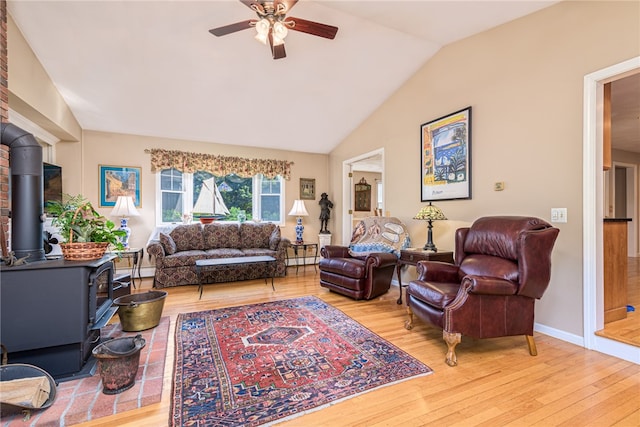 living room with ceiling fan, wood-type flooring, vaulted ceiling, and a wood stove