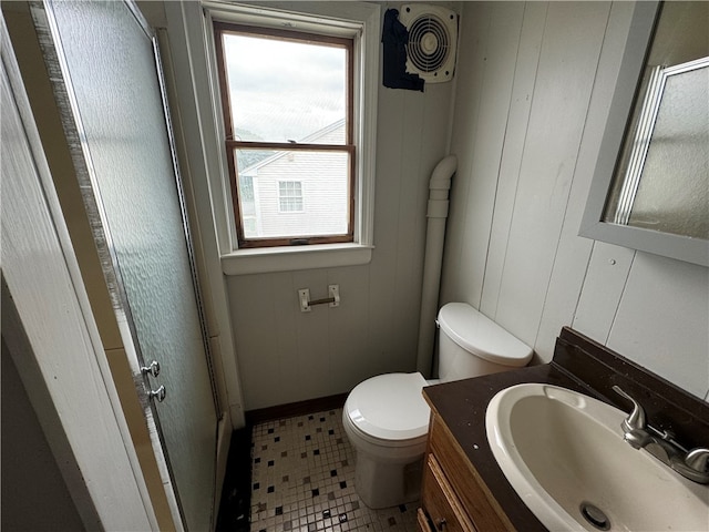 bathroom with toilet, tile patterned floors, walk in shower, wooden walls, and vanity