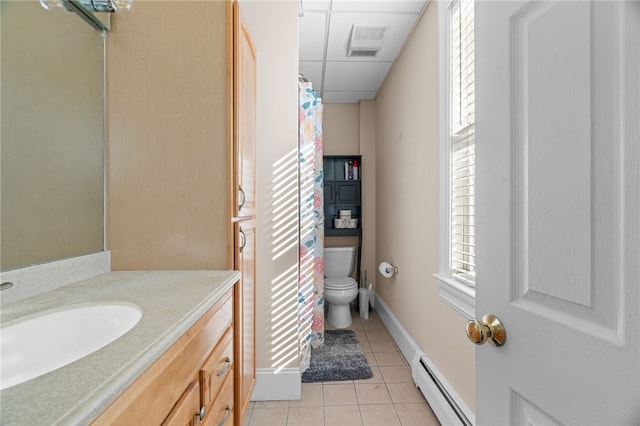 bathroom with toilet, tile patterned flooring, baseboard heating, vanity, and a paneled ceiling