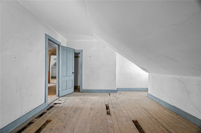 additional living space with light hardwood / wood-style floors and vaulted ceiling