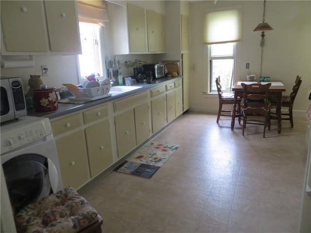 kitchen featuring cream cabinets, pendant lighting, a healthy amount of sunlight, and washer / clothes dryer