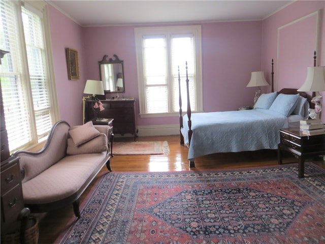 bedroom with ornamental molding, hardwood / wood-style floors, and multiple windows